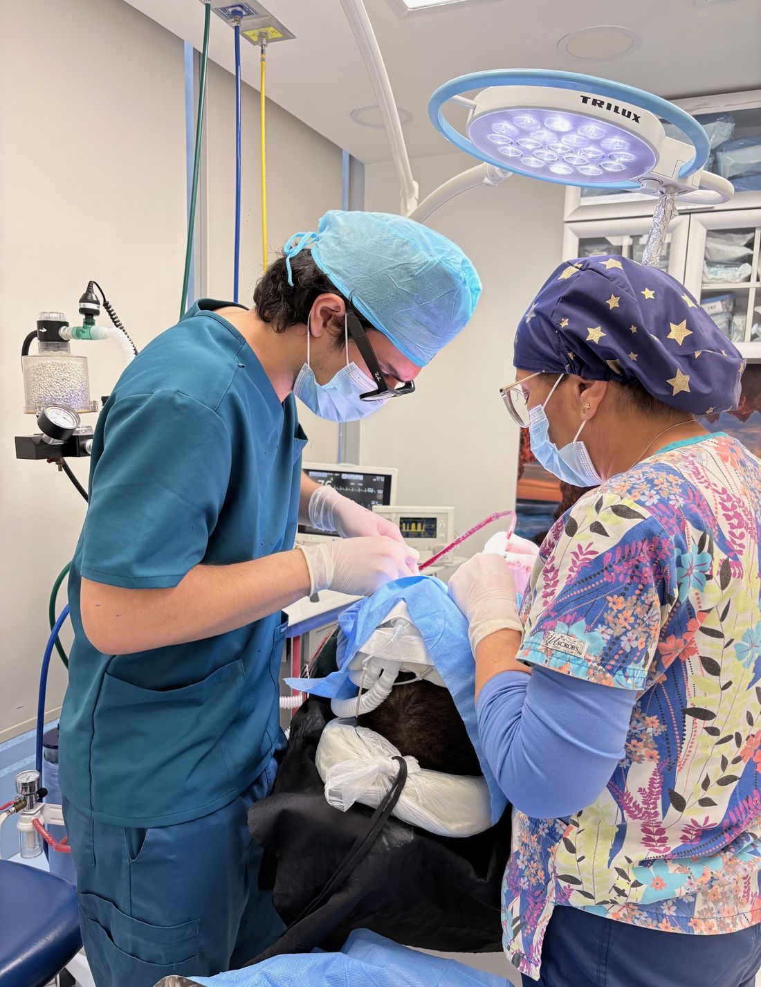 El Dr. López operando en pabellón junto a su asistente, con el paciente cubierto por campo quirúrgico